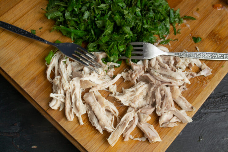 Prepping Chicken And Greens Shredded chicken and chopped green nettles on a cutting board