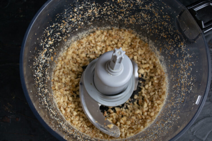 Crushing the nuts Coarsely chopped walnuts inside a food processor bowl