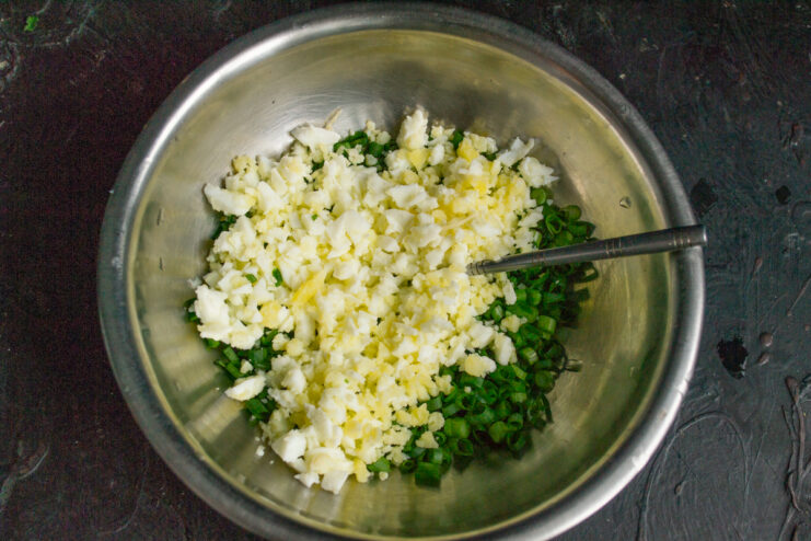 Adding eggs to the scallions Chopped hard-boiled eggs mixed with fresh scallions