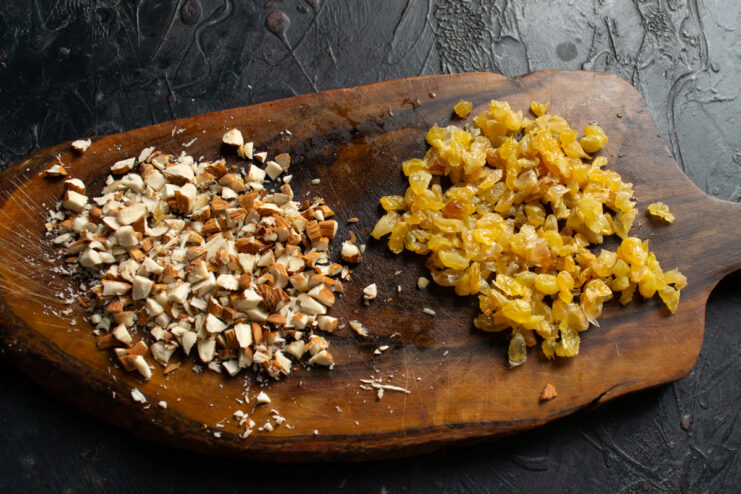 Preparing the nut filling Finely chopping toasted almonds and plump raisins on a wooden cutting board