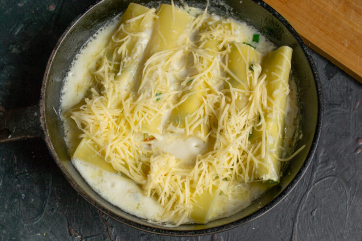 Melting cheese over the cannelloni Cannelloni topped with grated cheese melting in a pan
