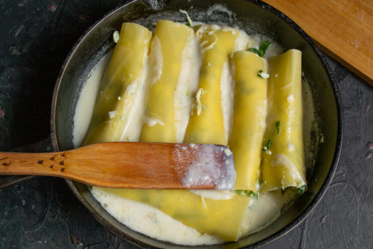 Simmering cannelloni in the sauce Stuffed cannelloni simmering in creamy sauce in a skillet