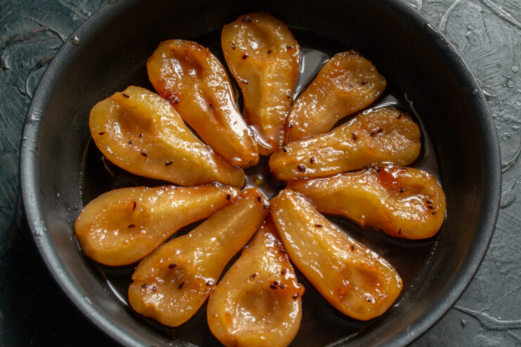 Caramelized Pears in Syrup Tender caramelized pear halves resting in rich syrup inside a pan