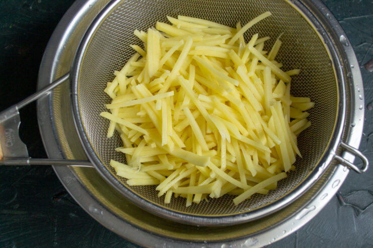 Draining potatoes in a sieve Shoestring potatoes draining in a metal sieve