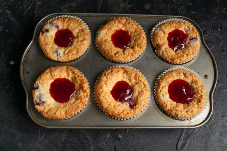 Adding red gooseberry jam to the center of baked muffins