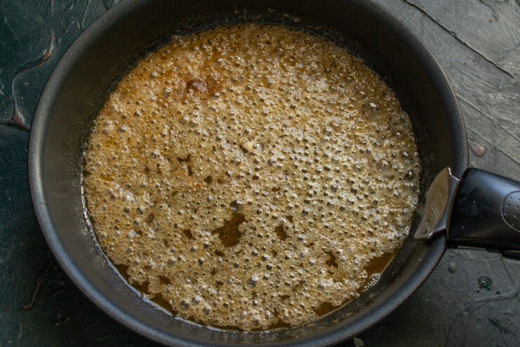 Bubbling golden caramel simmering in a skillet.