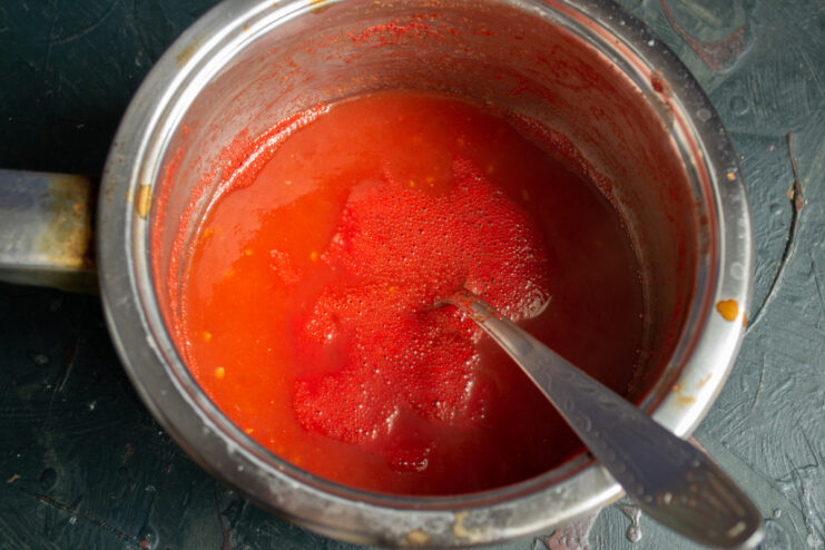Boiling the fresh tomato juice Boiling homemade tomato juice in a pot with reducing foam