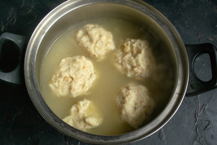 Cooking the dumplings in the soup Large bean dumplings simmering gently in a pot of chicken soup