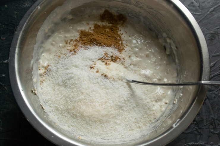 Adding coconut and spices Shredded coconut and ground spices in a mixing bowl