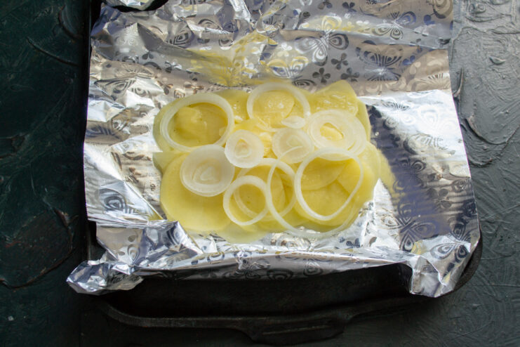 Adding the onion Thin onion rings scattered over sliced potatoes