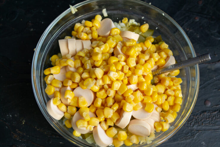 Canned sweet corn Canned corn added to sausages and pickles in a bowl.