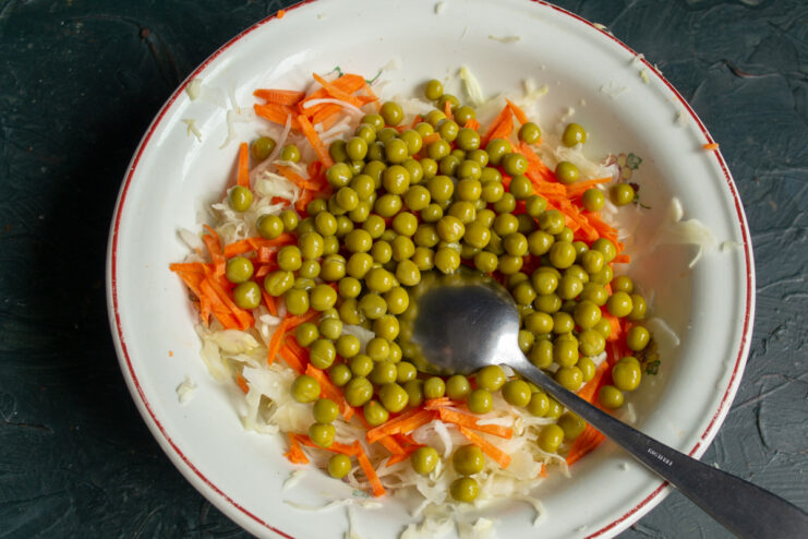 Adding canned green peas Canned green peas added to shredded cabbage and carrots in a mixing bowl