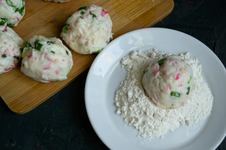 Initial flour breading Crab croquette being rolled in all-purpose flour