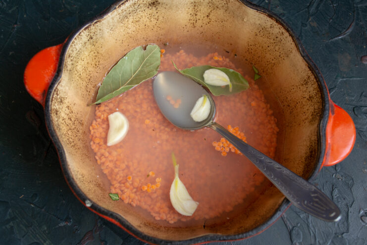 Cooking the Red Lentils Red lentils boiling in a pot with water, garlic, and bay leaves