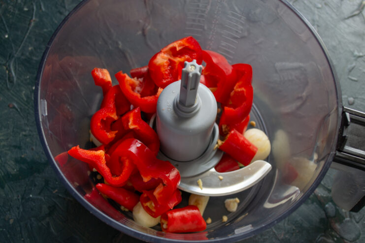 Mixing Vegetable Ingredients Red bell pepper chunks added to the food processor with chilies and garlic.