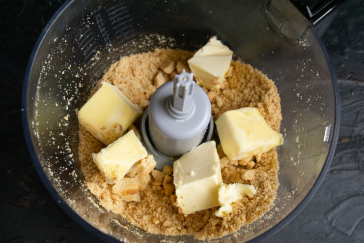 Combining cookies and butter Crushed shortbread cookies topped with chunks of softened butter in a blender