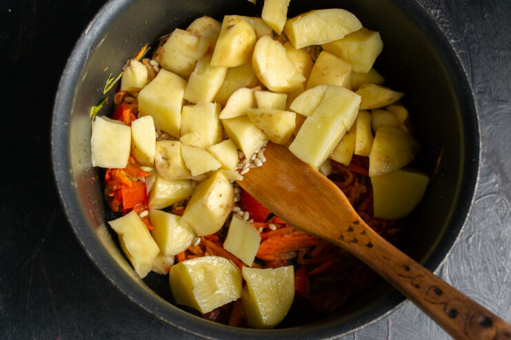 Adding Potatoes To Rassolnik Large potato cubes added to the rest of the ingredients in the pot.