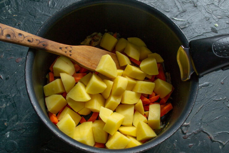 Adding the potatoes Large potato cubes added to the vegetable mixture in the pot