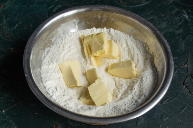 Rubbing cold butter into the flour Cold butter cubes added to the flour mixture for shortcrust pastry