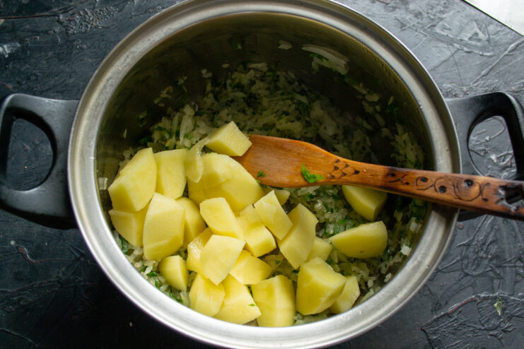 Adding diced potatoes Diced potatoes being added into a pot with toasted rice and vegetables