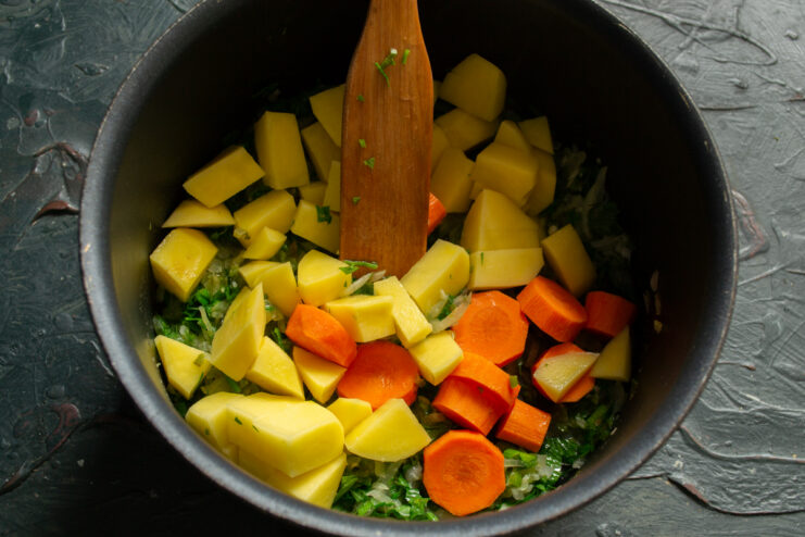 Building the vegetable base Diced potatoes and thick carrot slices added to the pot with the onion base