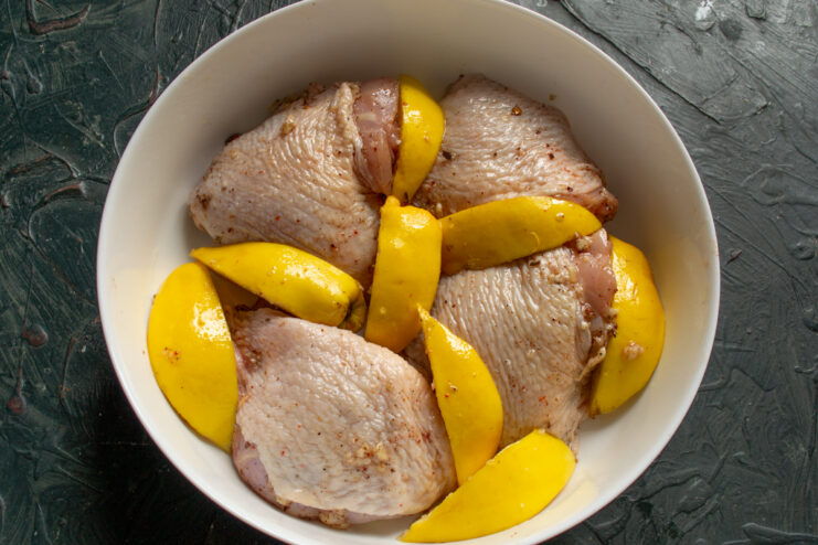 Adding Quince Slices Raw chicken and sliced quince arranged in a baking pan