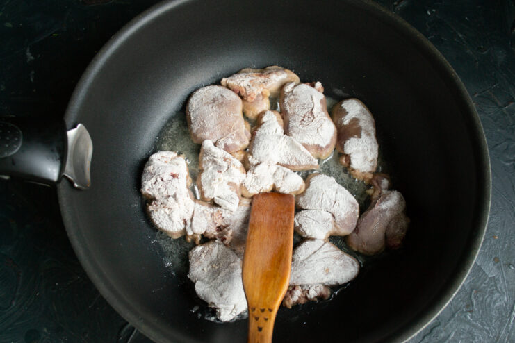Stir-Frying the Chicken Livers Chicken livers sizzling in hot oil inside a wok