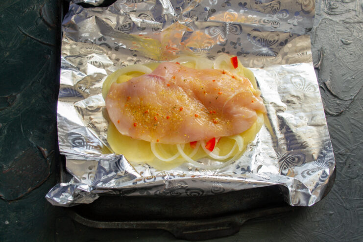 Placing the chicken Seasoned chicken fillet resting on top of the vegetables