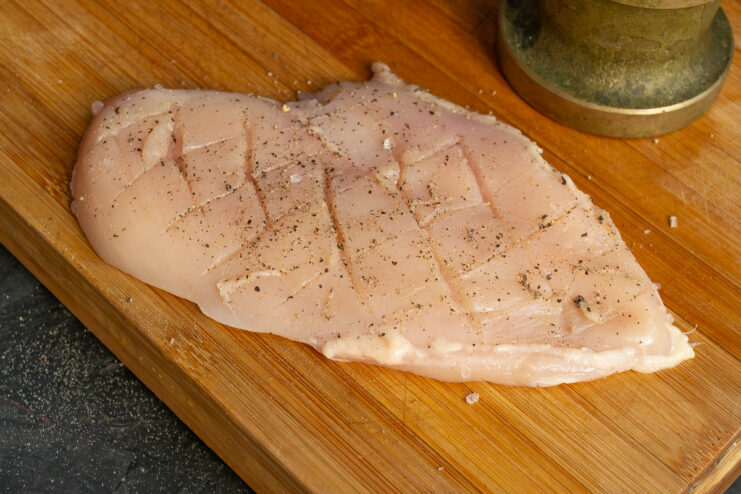 Seasoning the chicken Rubbing spices and a drop of oil into the scored chicken fillet