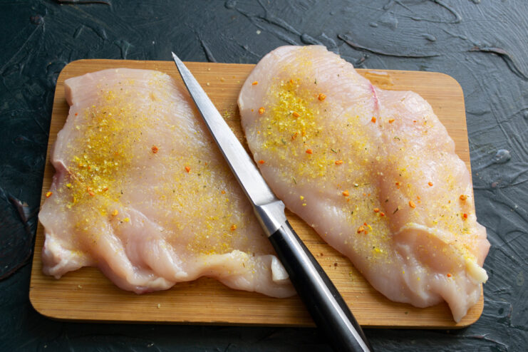 Preparing the chicken Seasoned chicken breast fillets resting on a cutting board