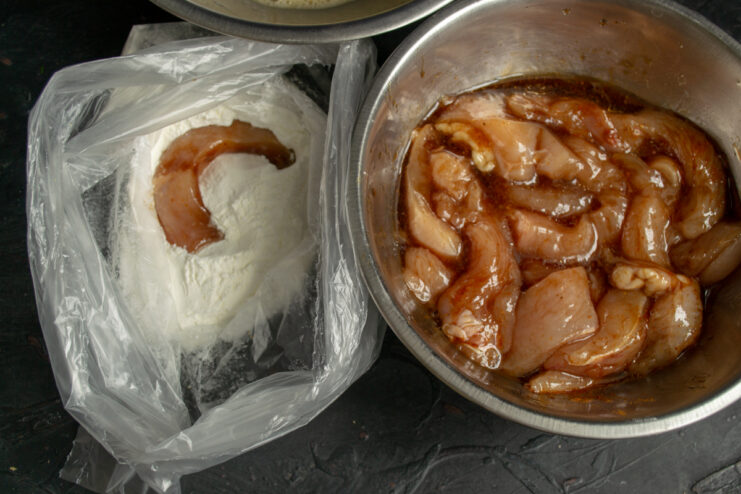 Coating chicken in starch Adding raw chicken pieces into a plastic bag with starch