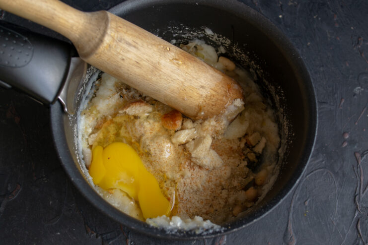 Adding the egg to the dough Raw egg added to the mashed bean and semolina dumpling mixture