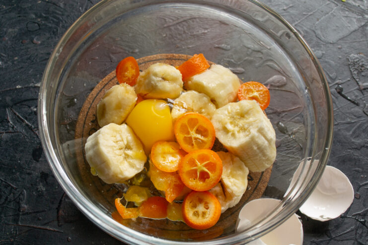 Adding an egg A raw egg added to the fruit mixture in a glass bowl