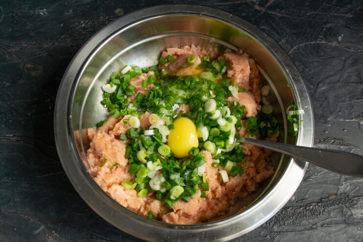 Binding ingredients A raw egg added to the bowl with minced fish and green onions.