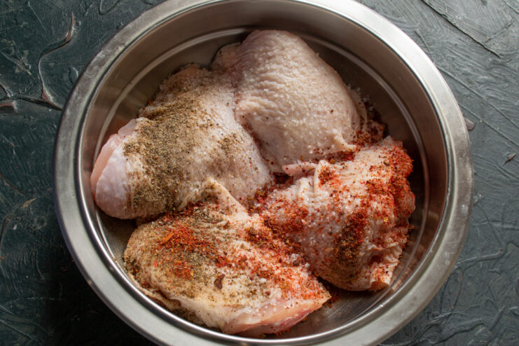 Marinating The Chicken Raw chicken thighs seasoned with paprika and herbs