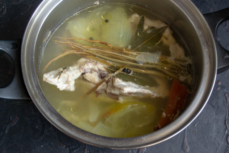 Simmering rich chicken broth Chicken broth simmering in a pot with roots, bay leaves, and peppercorns