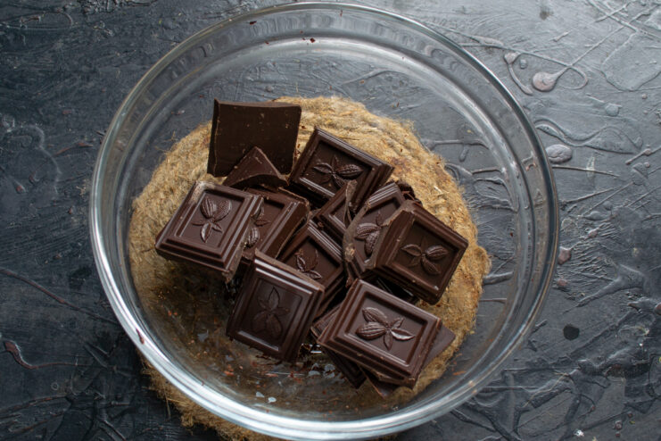 Melting the dark chocolate Broken pieces of dark chocolate softening and melting in a glass bowl over a double boiler
