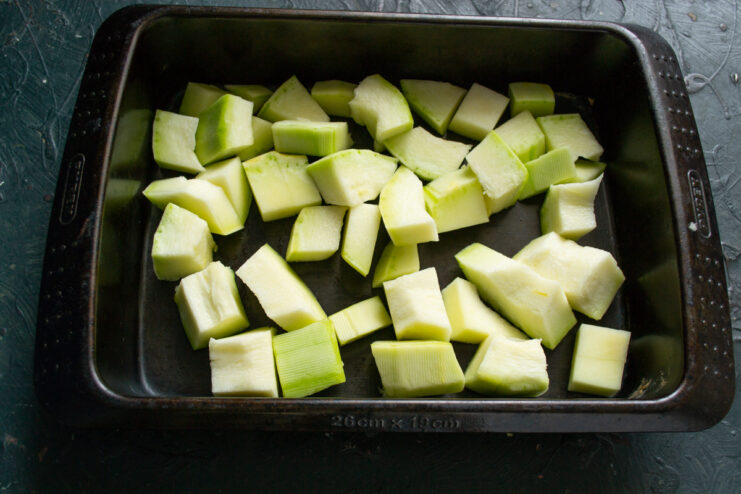 Layering vegetables in the pan Diced zucchini layered in a deep roasting pan