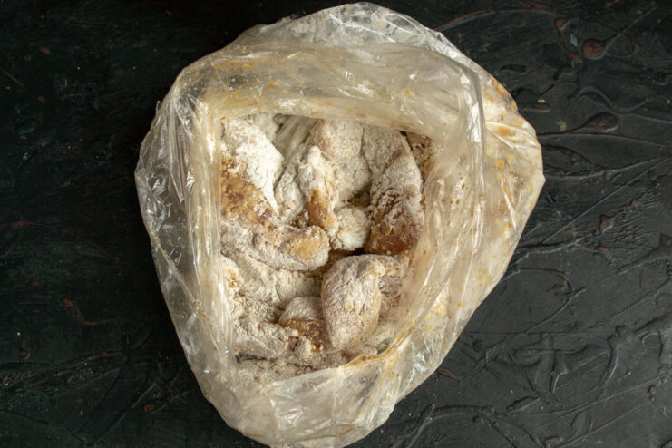 Shaking the bag to coat chicken evenly Chicken pieces evenly coated with starch inside a plastic bag