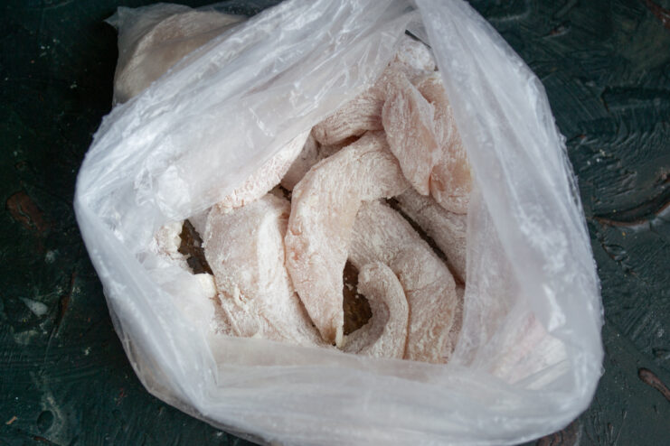 Coating chicken in starch Raw chicken pieces tossed in starch inside a plastic bag