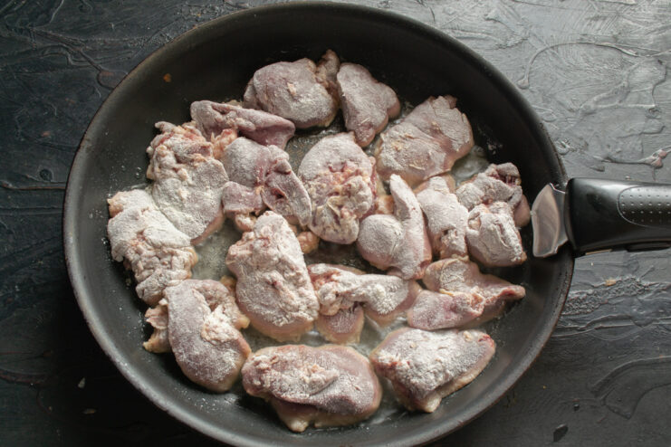 Searing the liver Flour-dredged chicken liver pieces searing to a golden crust in a large skillet.