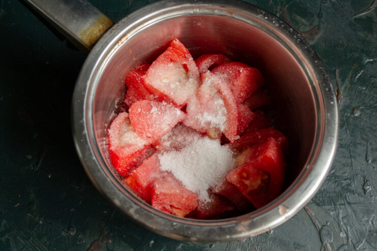Mixing tomatoes with sugar and salt for the juice Chopped overripe tomatoes in a saucepan mixed with salt and sugar