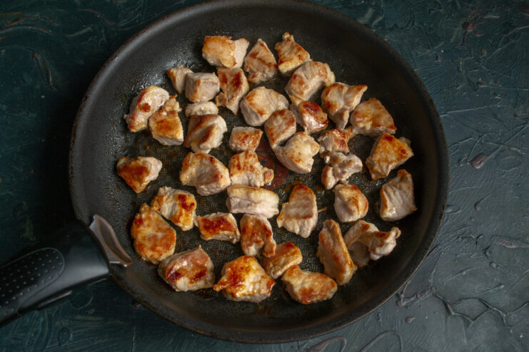 Searing the Pork Bite-sized pieces of pork searing in a skillet to a golden brown crust.