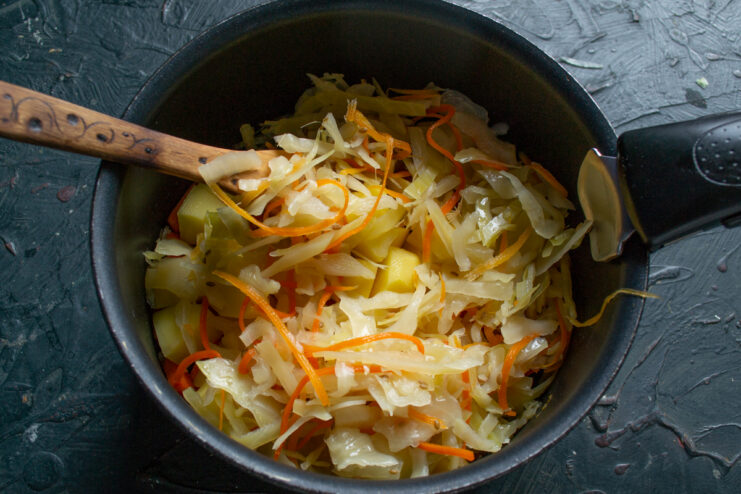 Adding the sauerkraut Sauerkraut layered on top of other vegetables in a cooking pot