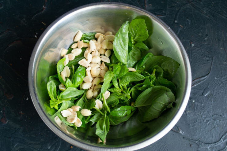 Pesto ingredients Fresh green basil leaves and roasted peanuts gathered in a bowl