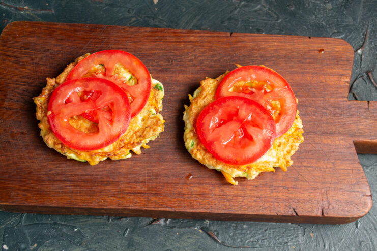 Assembling the healthy fishburger Fresh tomato slices placed on top of vegetable fritters
