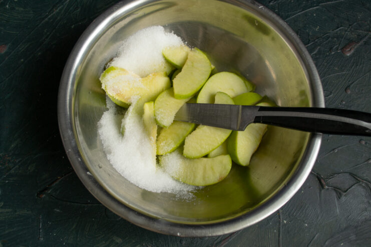 Preparing the Apples Sliced apples tossed with sugar in a bowl