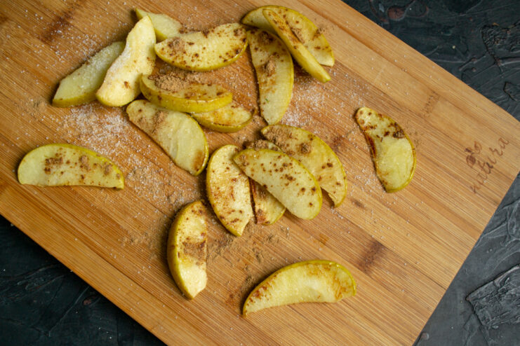 Preparing the apple filling Warm apple slices coated with cinnamon and sugar on a board