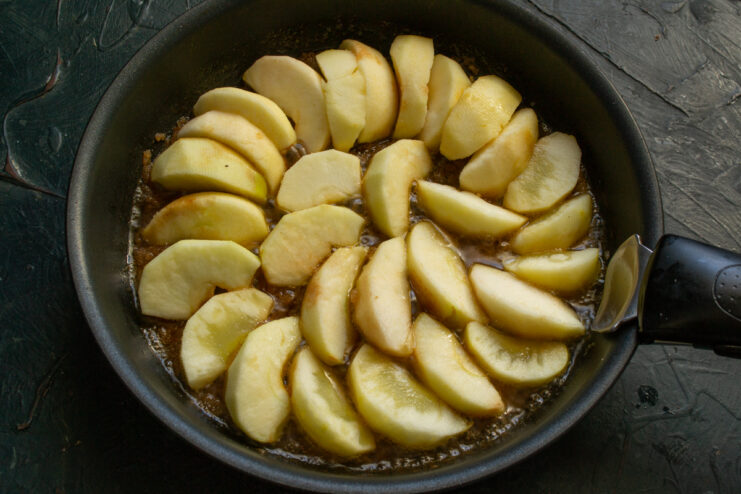 Apple slices neatly arranged in a fan shape in a skillet with caramel.