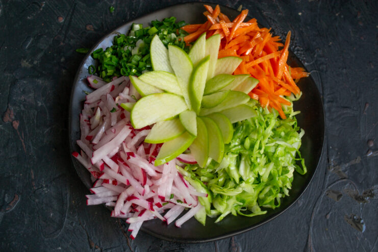 Apple slices arranged in the shape of a flower in the center of the salad
